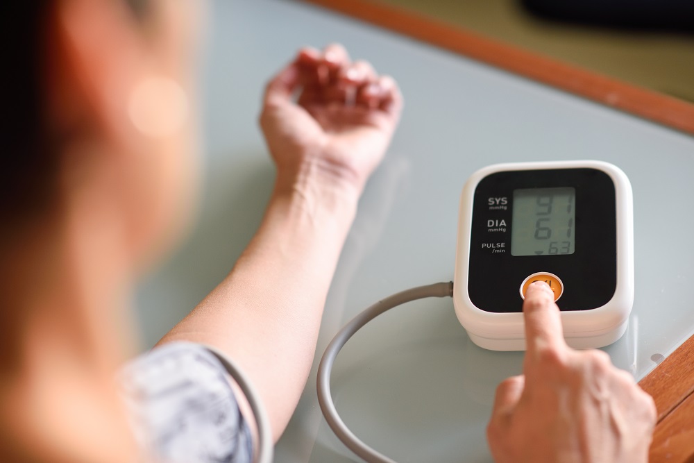 Woman with low blood pressure measuring with an electronic measurement device at home